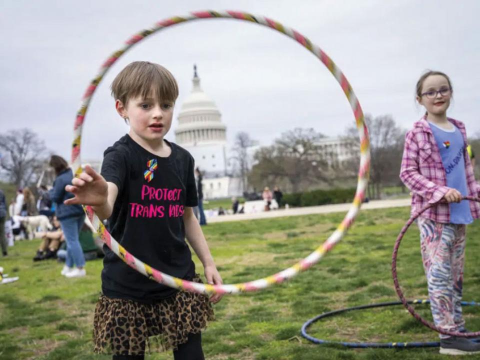 Mac Gordon Frith, 6, left, who is here supporting his sibling, Caleta Frith, 9, right, who is non-binary, uses a hula hoop during a rally on the Transgender Day of Visibility, Friday, March 31, 2023, by the Capitol in Washington. Transgender people and their allies gathered at venues across the country Friday as part of an annual, international recognition of transgender resilience, an observation that this year comes amid what some denounced as  an increasingly hostile climate. (AP Photo/Jacquelyn Martin)